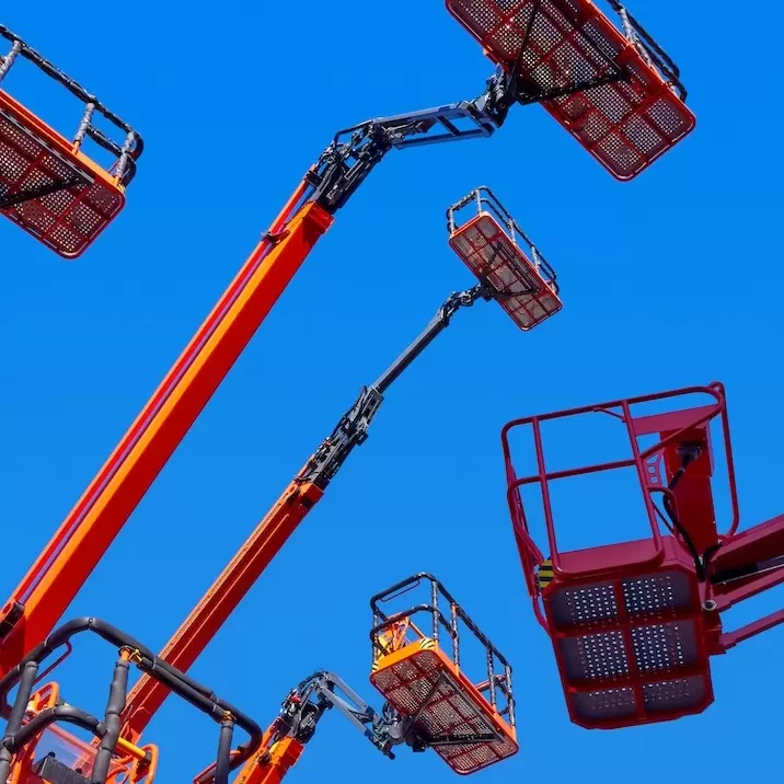 Big group of articulating cranes, baskets and hydraulic arms high in a clear blue sky, low angle perspective shot.